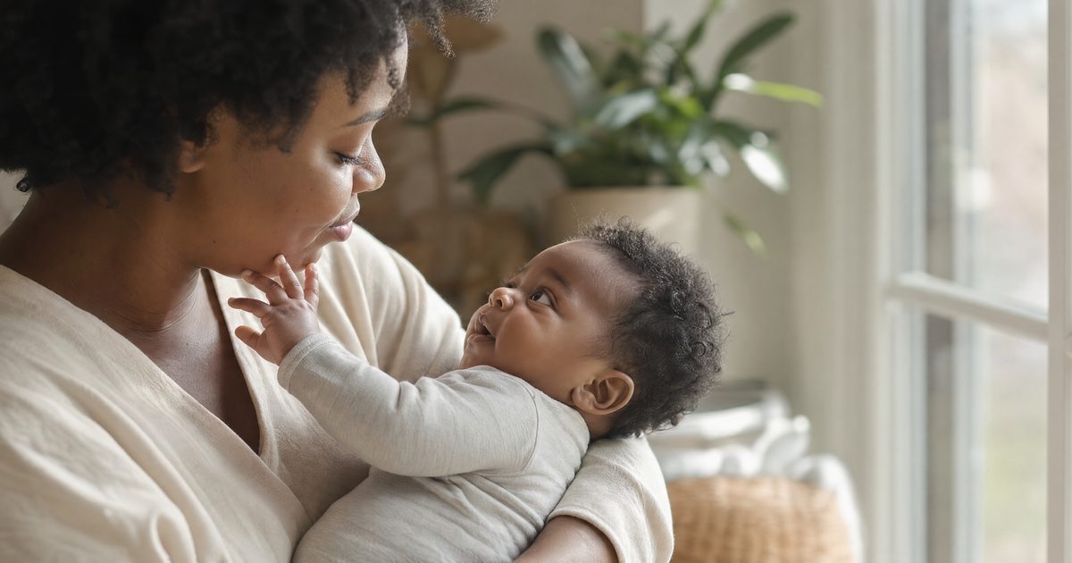 Mutter hält ihr neugieriges Baby am hellen Fenster